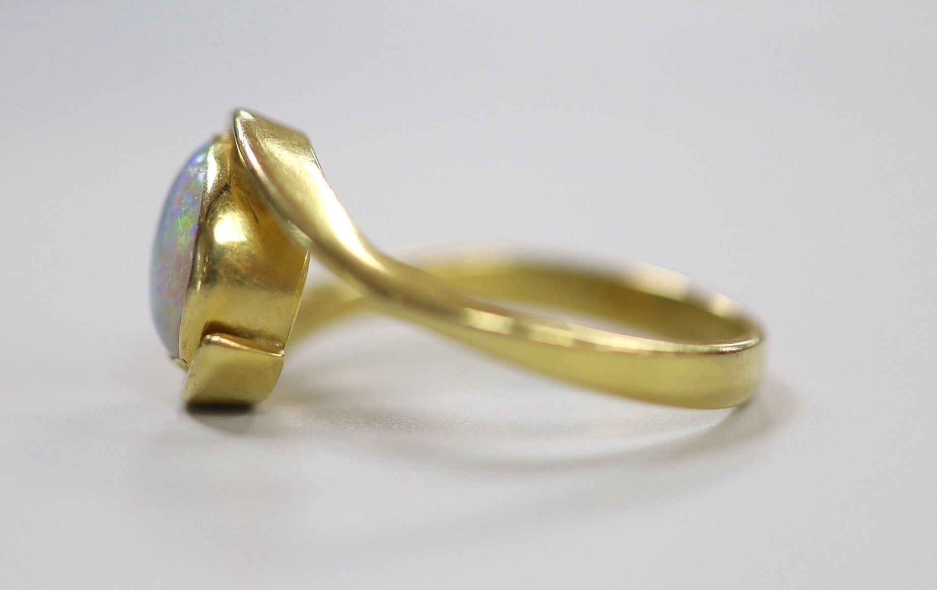 An 18ct and single stone oval white opal set ring, with crossover shoulders, size Q, gross weight 5.6 grams.